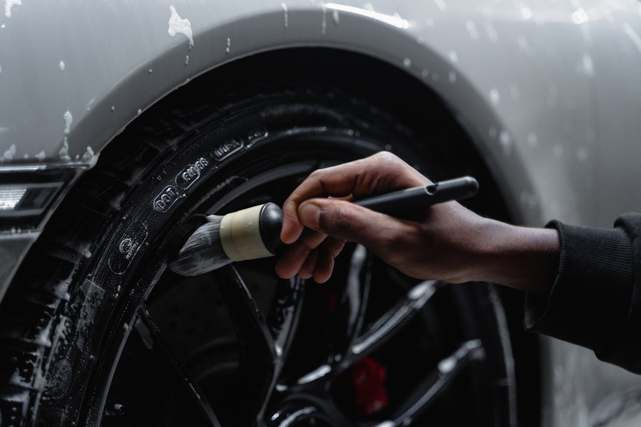 service-01 Detailed shot of a hand using a brush to clean a car tire and wheel during a wash.